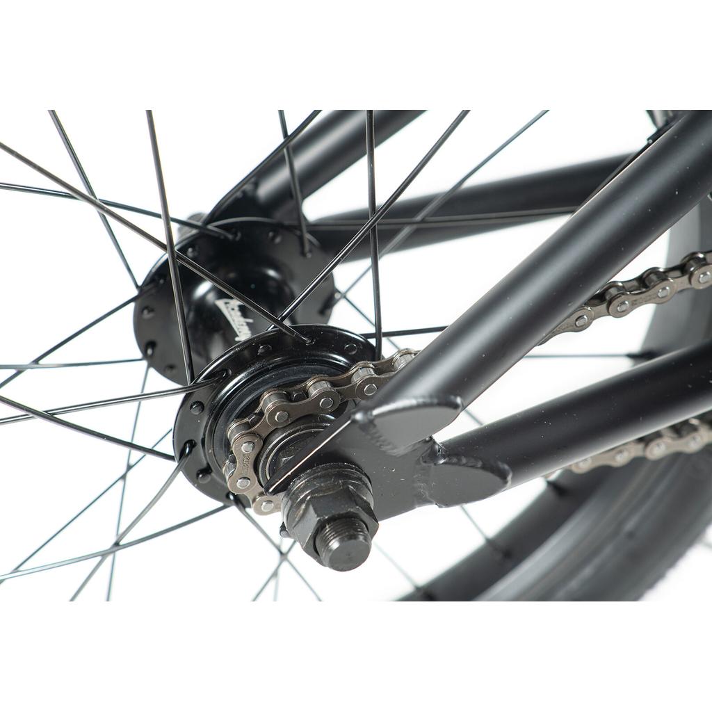 Close-up of the Academy Inspire 16 Inch Bike's rear wheel hub, featuring black spokes, a chain, axle, sealed hub, and part of the metal frame.