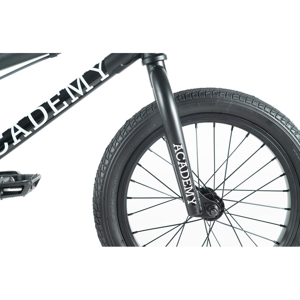 Close-up of the Academy Inspire 16 Inch Bike's front wheel and fork, displaying "ACADEMY" in white on the frame and fork, plus durable sealed hubs for smooth performance.