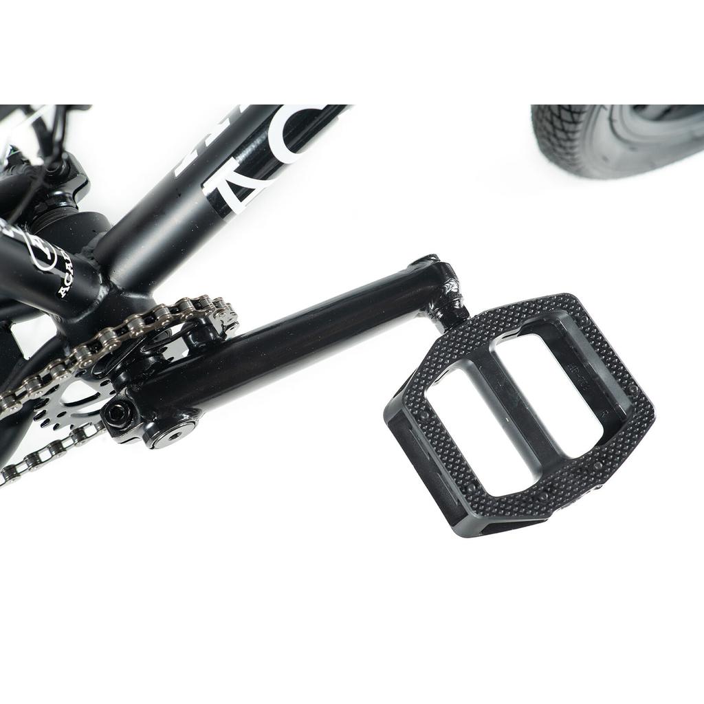 Close-up of a black pedal, crank arm, and chain on a white background—highlighting the Academy Inspire 18 Bike, ideal for BMX riders with its 18-inch frame and durable double wall rims.