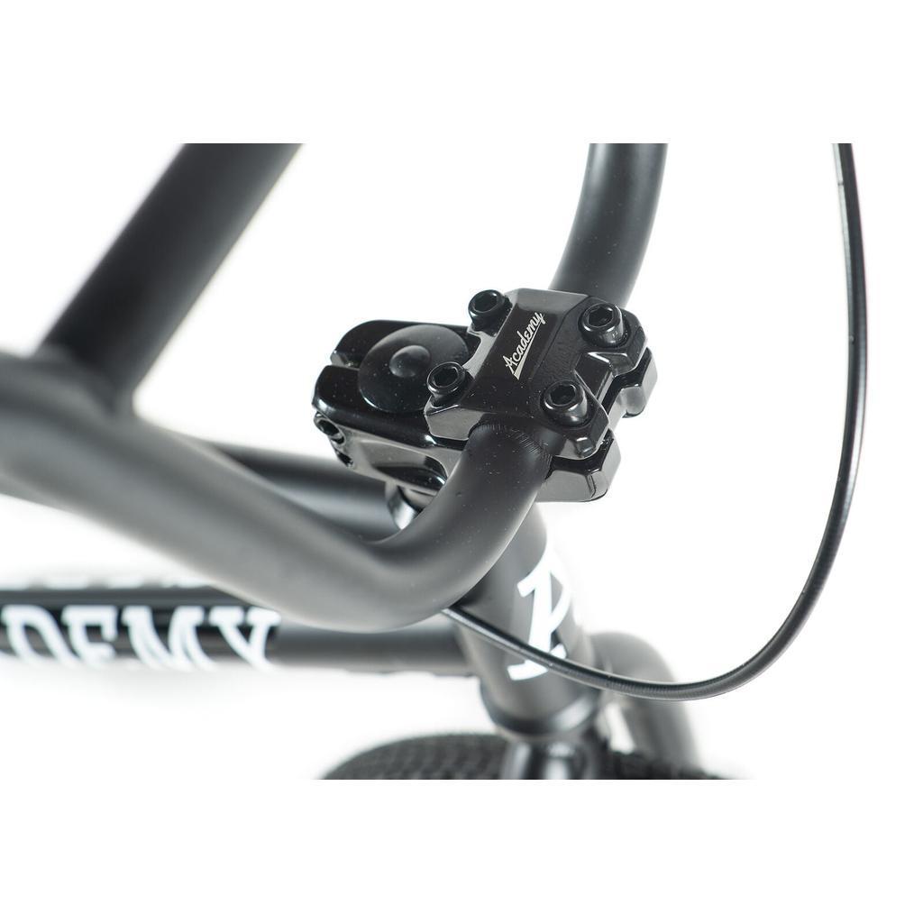 Close-up view of the Academy Inspire 18 Bike's handlebars and stem, showing visible bolts and a front brake cable.