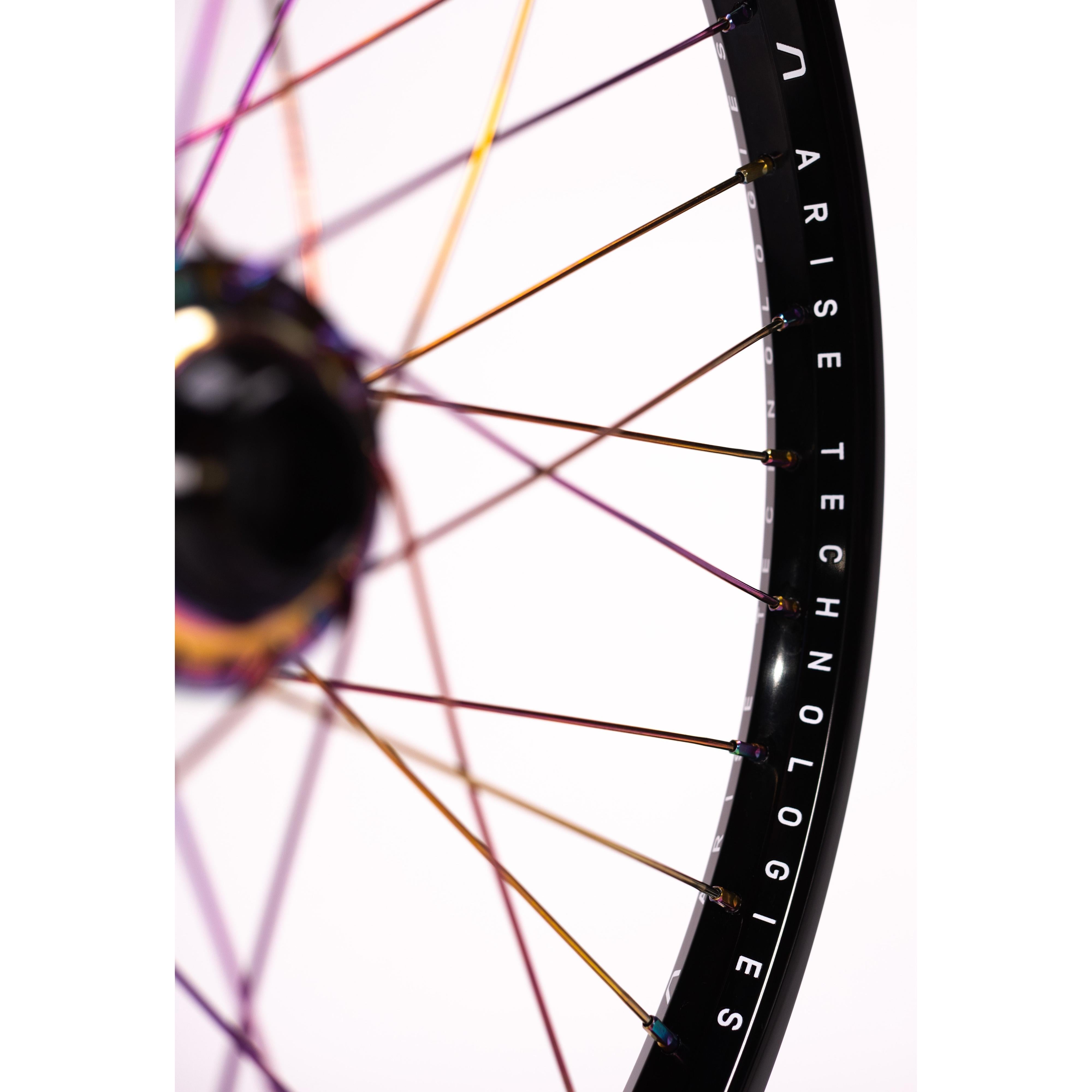 Close-up of the Arise Echo Oilslick Pro 20 Inch Wheelset showcasing iridescent spokes and tubeless-ready black rims with "ARISE TECHNOLOGIES" branding against a white background, designed for optimal engagement drive performance.
