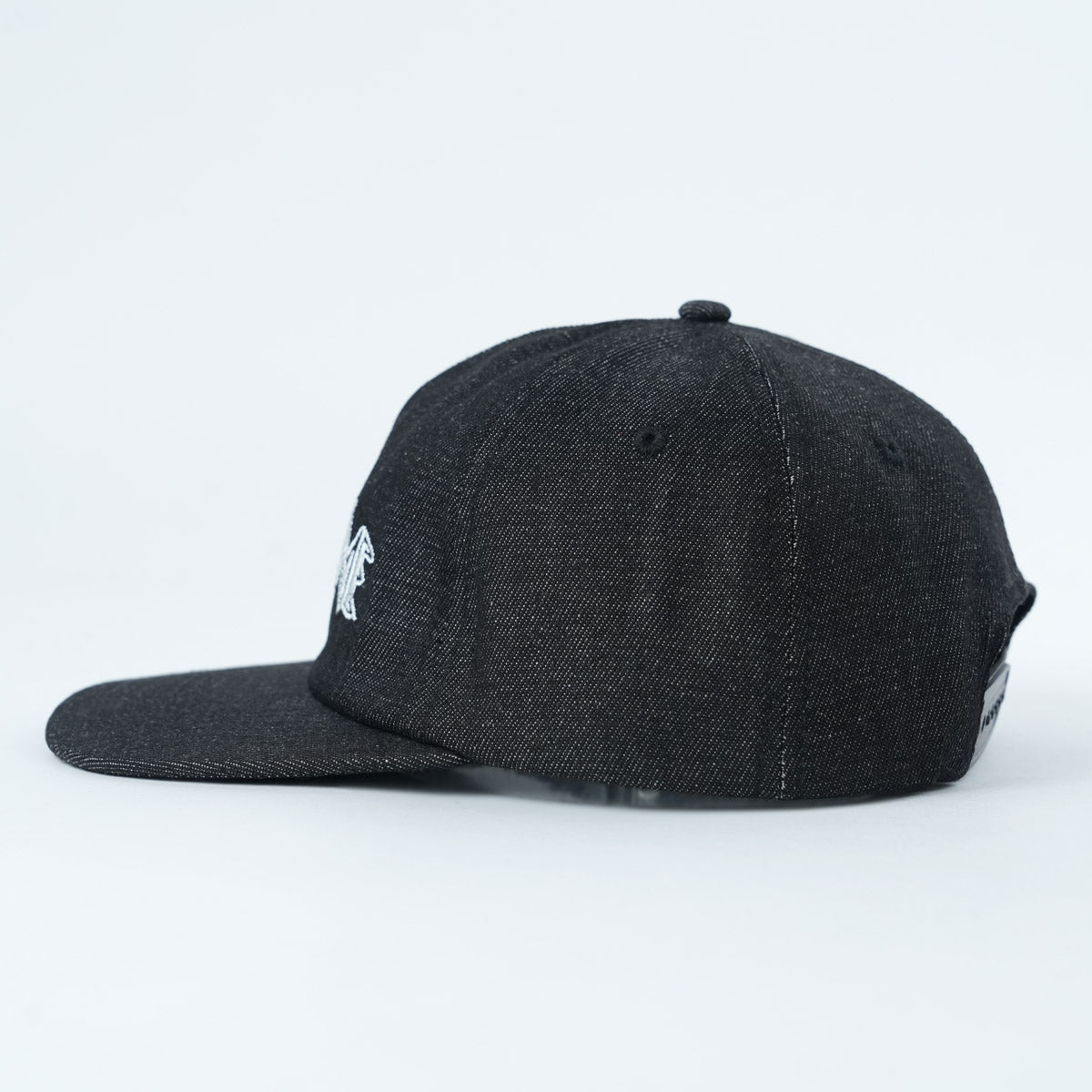 The Backbone Always Building Hat is a black denim unstructured 5-panel cap with a flat brim, shown from the side on a plain light background.