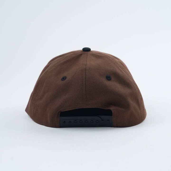 Backside view of the Backbone Always Building Hat, a brown baseball cap featuring an embroidered logo and a black adjustable snapback closure against a plain background.