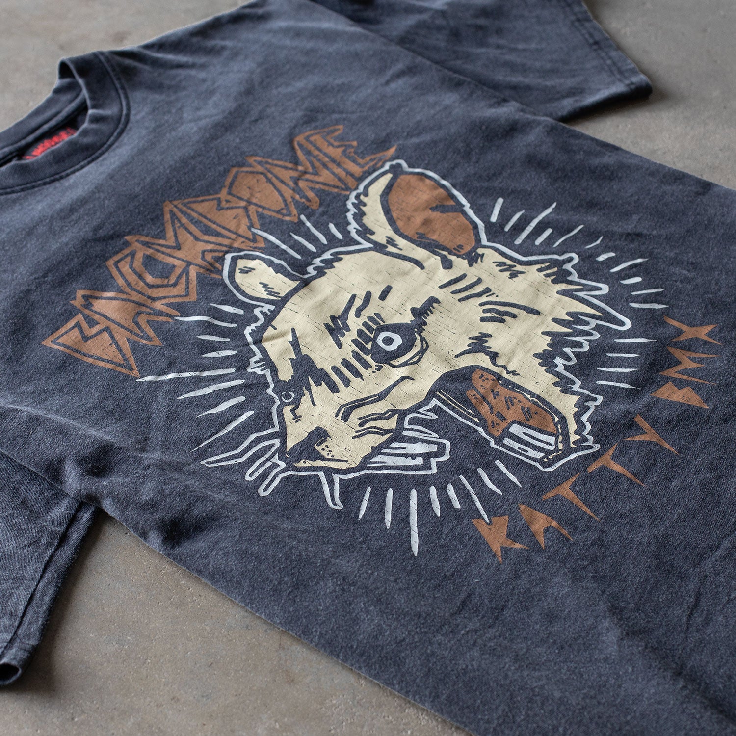 The Backbone Ratty BMX T-Shirt is a dark gray, vintage-style, boxy-fit tee made from premium cotton, featuring a large stylized animal head graphic and the words "BACKBONE" and "RATTLER".