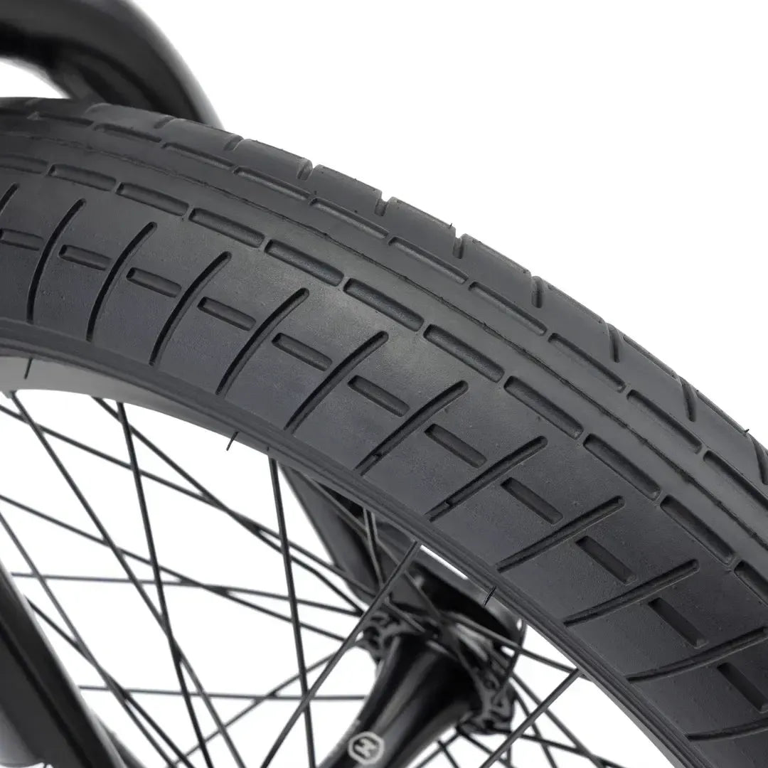 Close-up of the Kink Carve 16 Inch Bike (2026) black tire with tread pattern, mounted on a spoked wheel—ideal for kids and young BMX enthusiasts learning the basics.