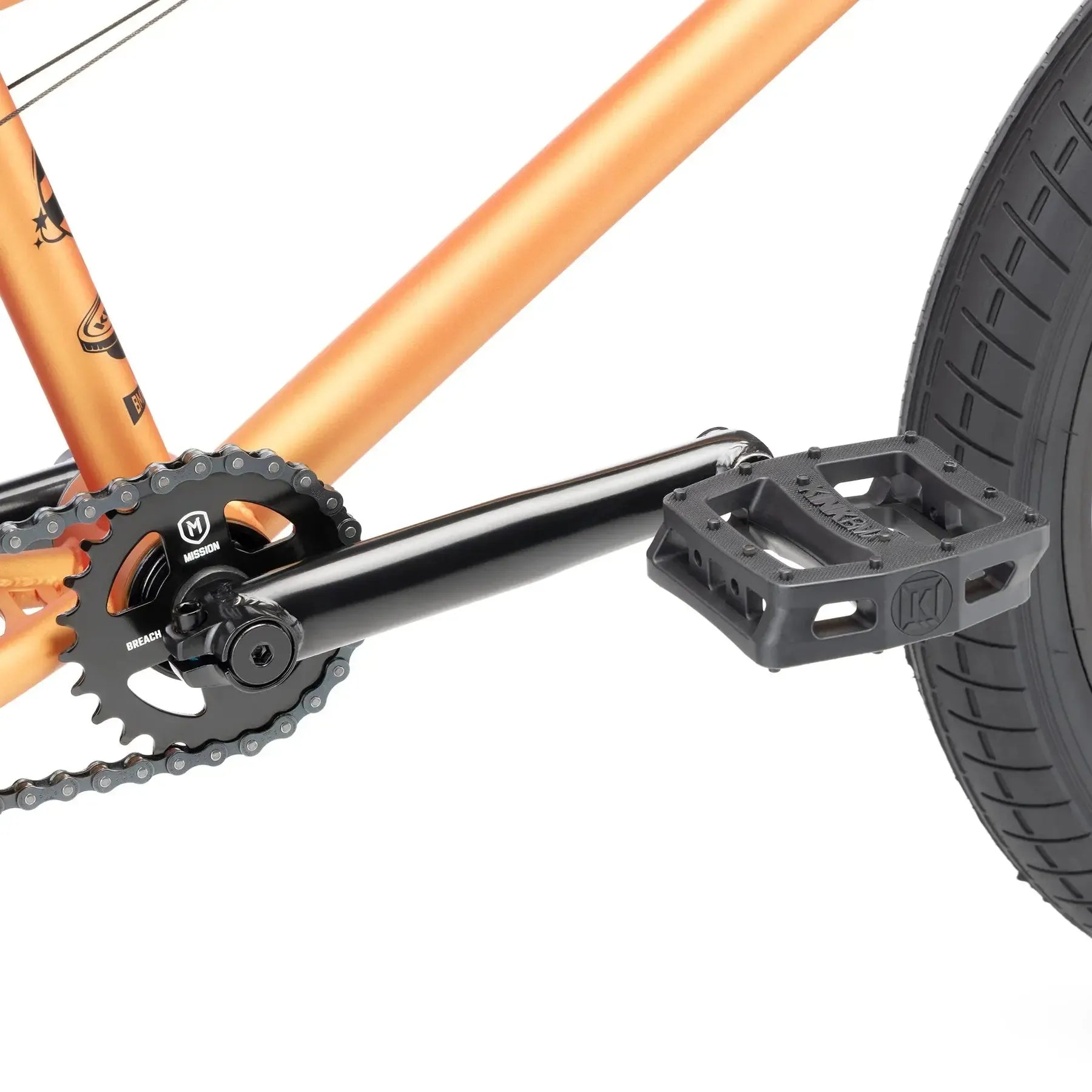Close-up of a black crank arm, chainring, and plastic pedal on an orange Kink Curb 20 Inch Bike (2026) frame with rear wheel.