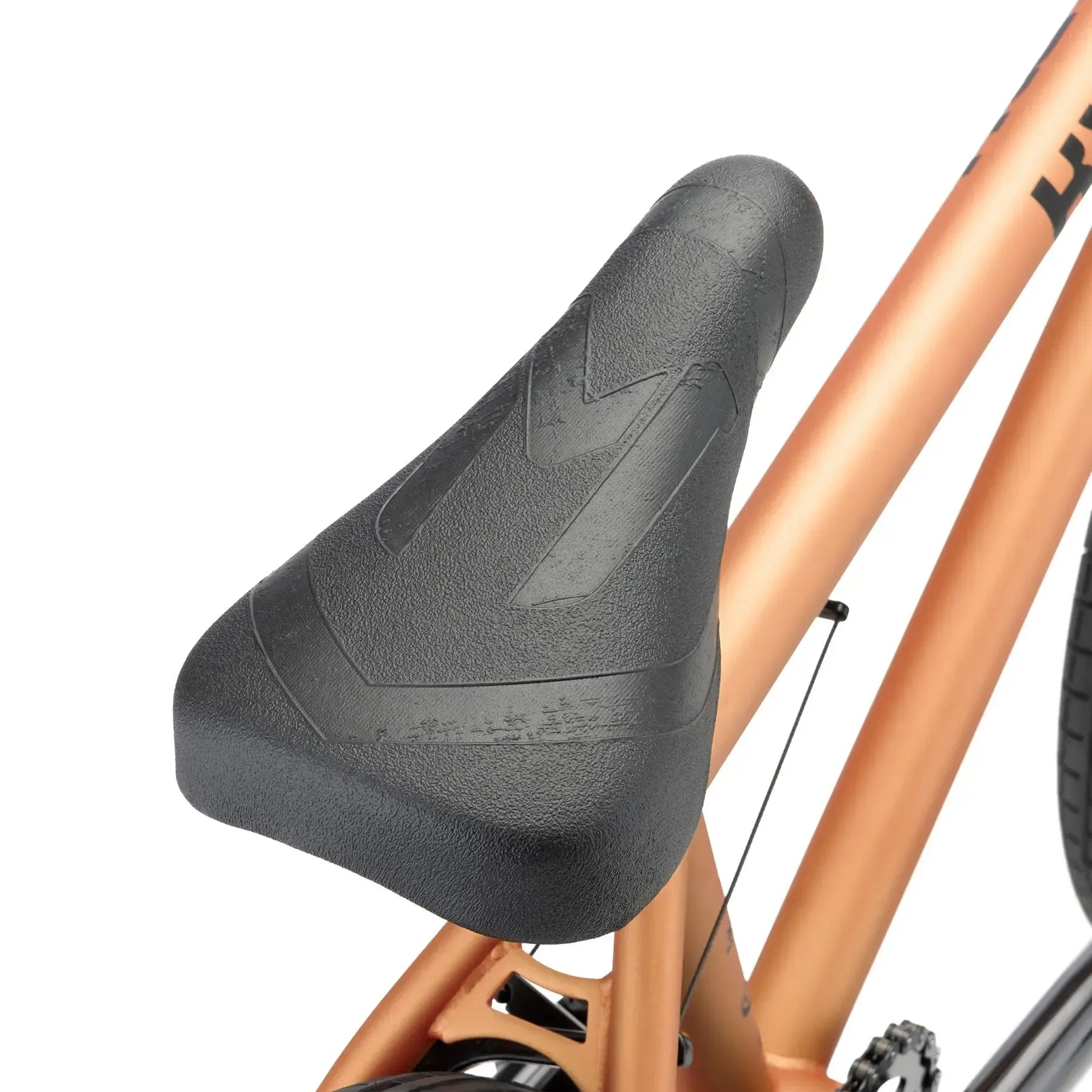 Close-up of a black seat on a metallic bronze Kink Curb 20 Inch Bike (2026), with the rear wheel and chain visible—a great BMX option for beginners.