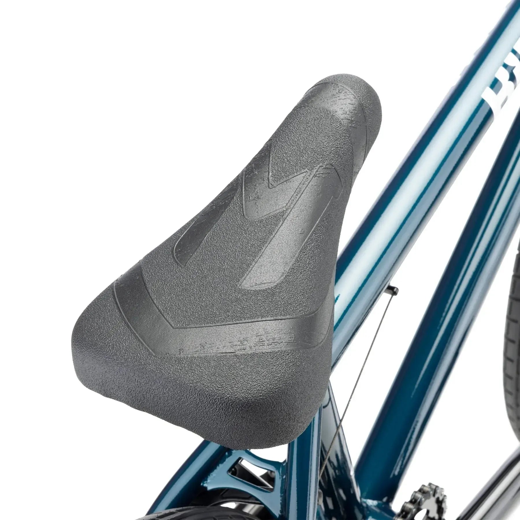 Close-up of a black textured seat on the Kink Curb 20 Inch Bike (2026), an entry-level BMX with a metallic blue frame—ideal for beginner riders.