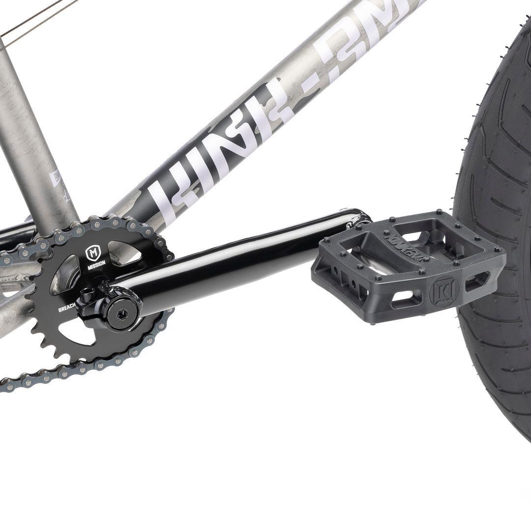 Close-up view of the Kink Launch LTD 20 Inch Bike's crankset, chainring, and platform pedal with sealed bearings attached to the frame and rear wheel.
