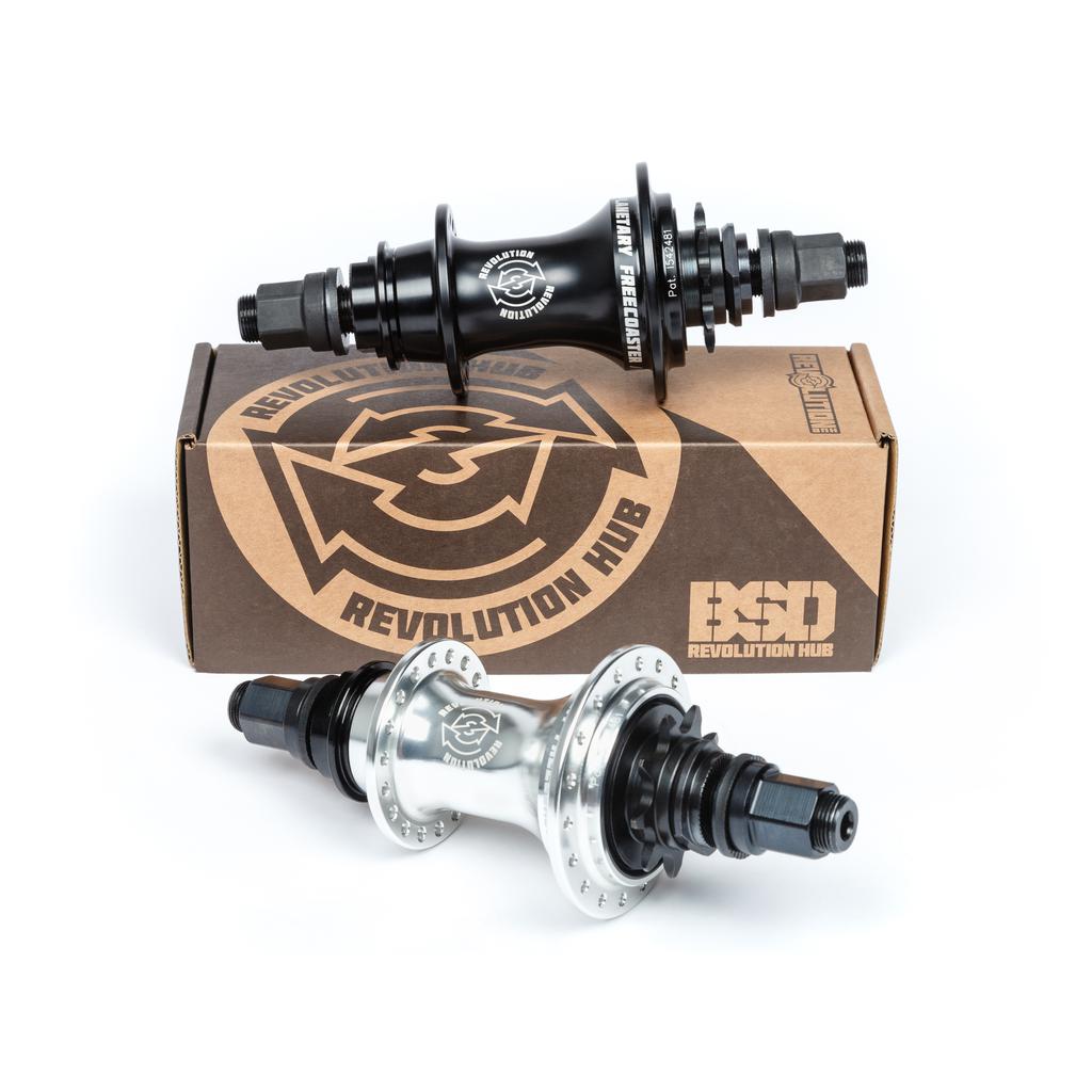 Two BSD Revolution Rear Freecoaster Hubs, with an innovative planetary clutch system, are shown in sleek black and silver next to branded cardboard packaging.