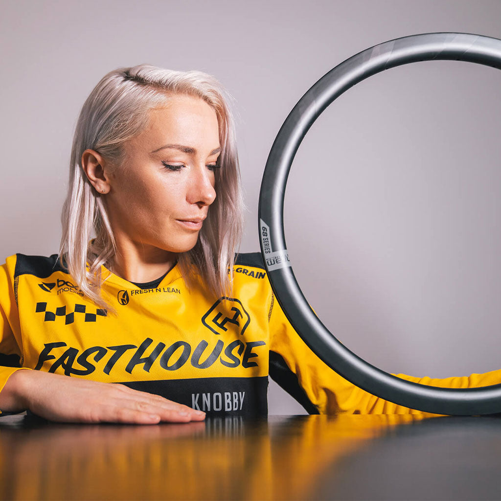 A woman in a yellow shirt is holding a Michram 68 Series carbon rim 406, emphasizing its strength.