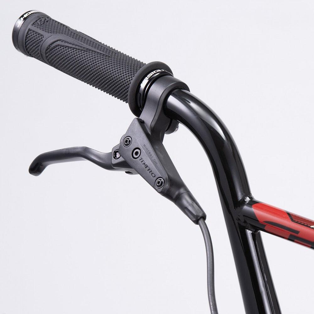 Close-up of the handlebar on a Chase Element Expert Bike, featuring a black textured grip and a Tektro brake lever. The handlebar, which is part of the Expert XL frame, is painted black with a notable section of red graphic.
