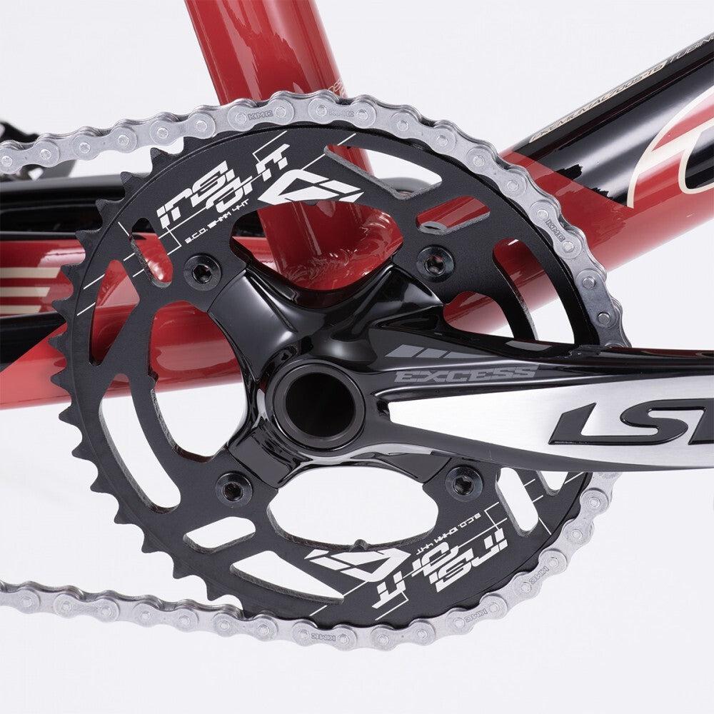 Close-up of a red bicycle crankset on the 2024 Chase Element Pro+ Cruiser Bike, showcasing the chainring, crank arm, and chain. The black chainring has white text and logos, including "Insight" and "LSR".