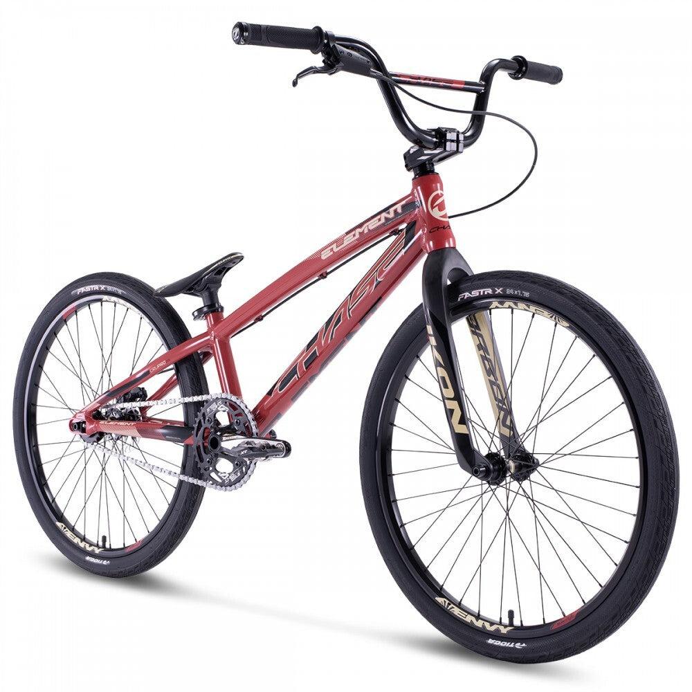 The Chase Element Pro+ Cruiser Bike is a red BMX race bike with black handlebars and tires. It features a sleek frame, Ikon carbon forks, front and rear brakes, and a single gear.