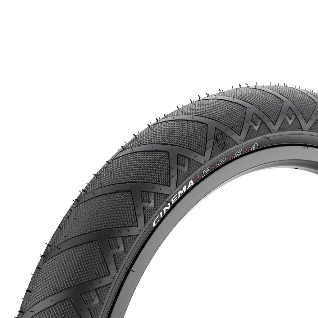 Close-up view of a black Cinema FPS Tyre BMX tyre with extra traction, featuring a textured, fast-rolling tread pattern and "CINEMA FPS" branding on the sidewall.