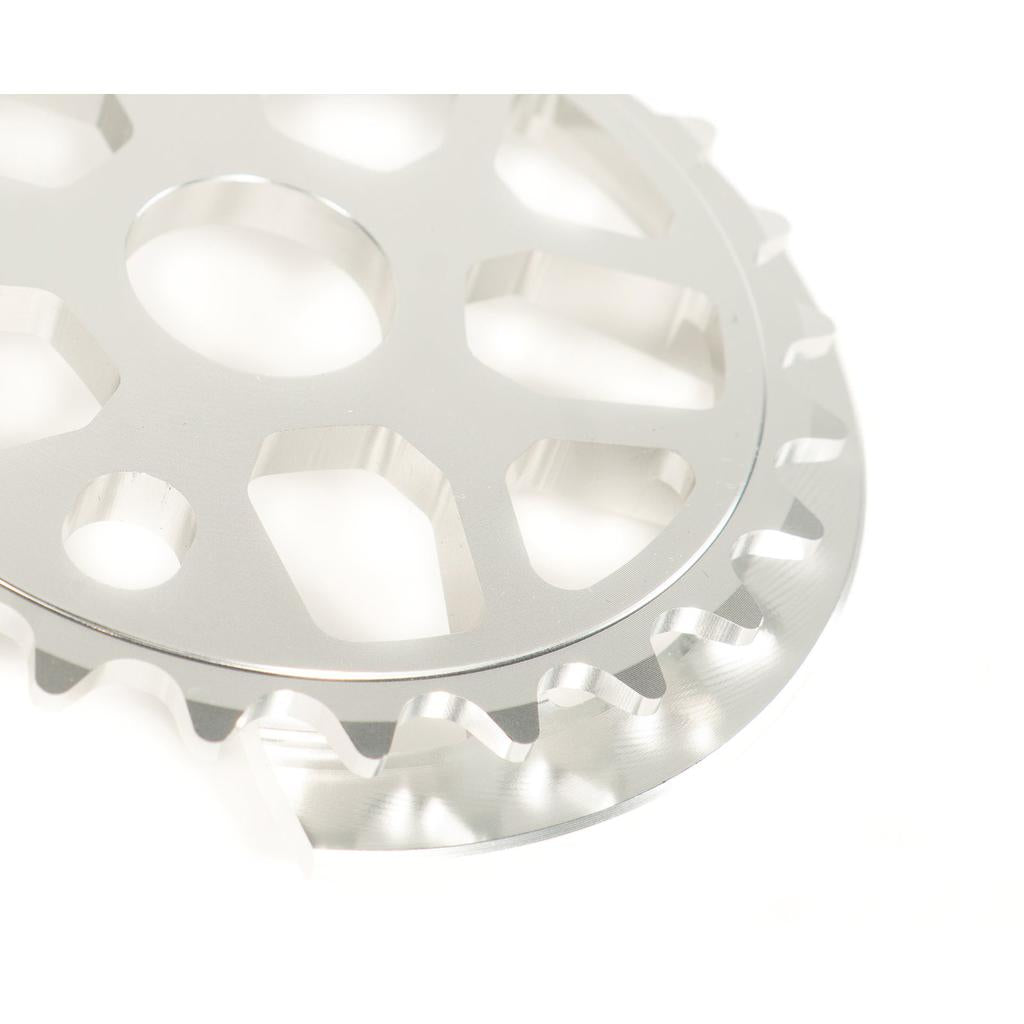 Close-up of the Colony Bish Guard Sprocket, crafted from 7075-T6 aluminum, with sharp teeth and hexagonal cutouts, against a white background.