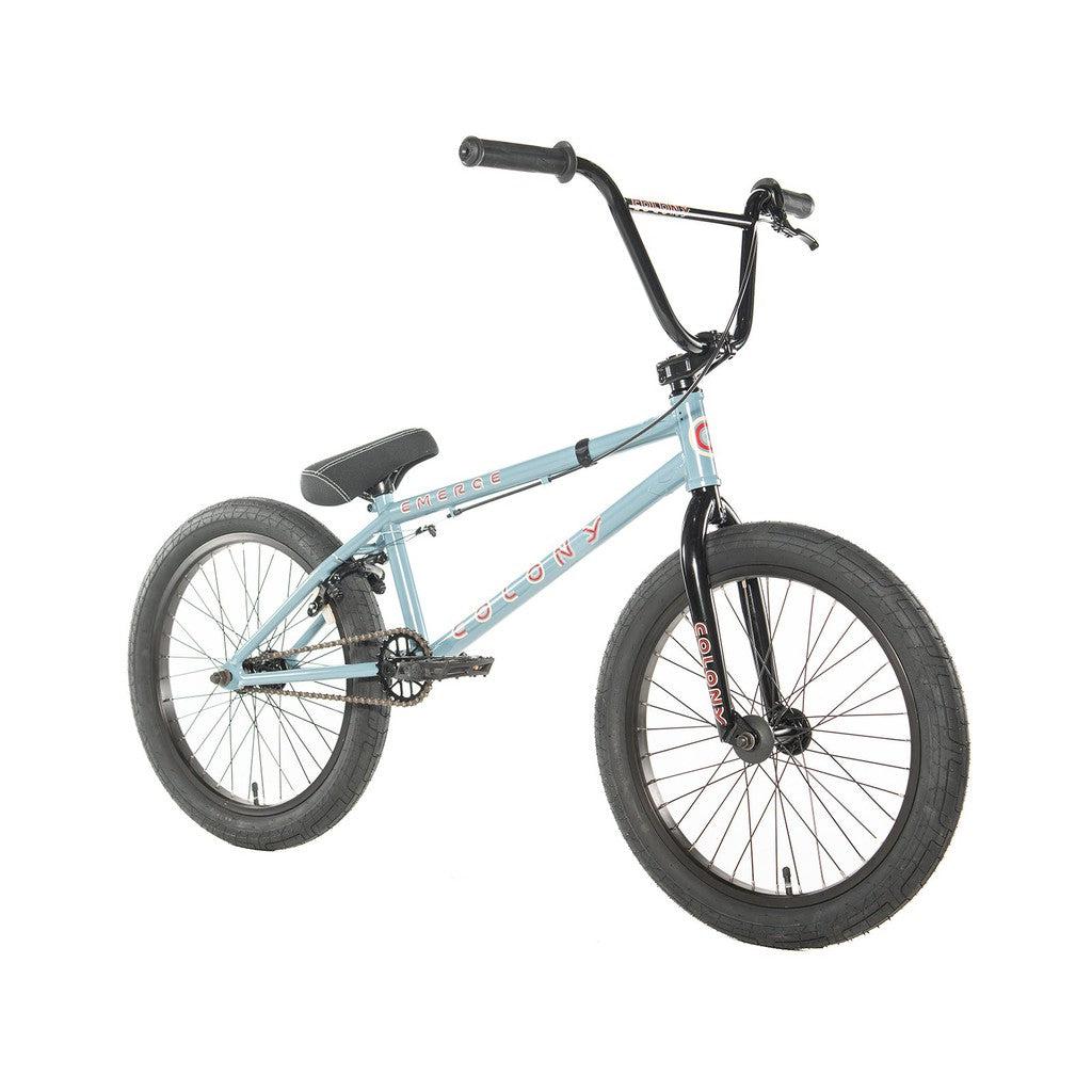 The Colony Emerge 20 Inch Bike showcases a captivating blue Chromoly frame, paired with black handlebars and wheels. The brand name "Colony" is strikingly emblazoned on the frame, perfectly complemented by a sleek black saddle.