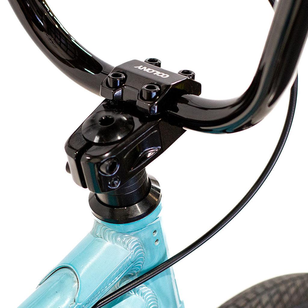 Close-up of a black handlebar and stem on a Colony Horizon 20 Inch Bike with a lightweight light blue alloy frame, showing the front brake cable.