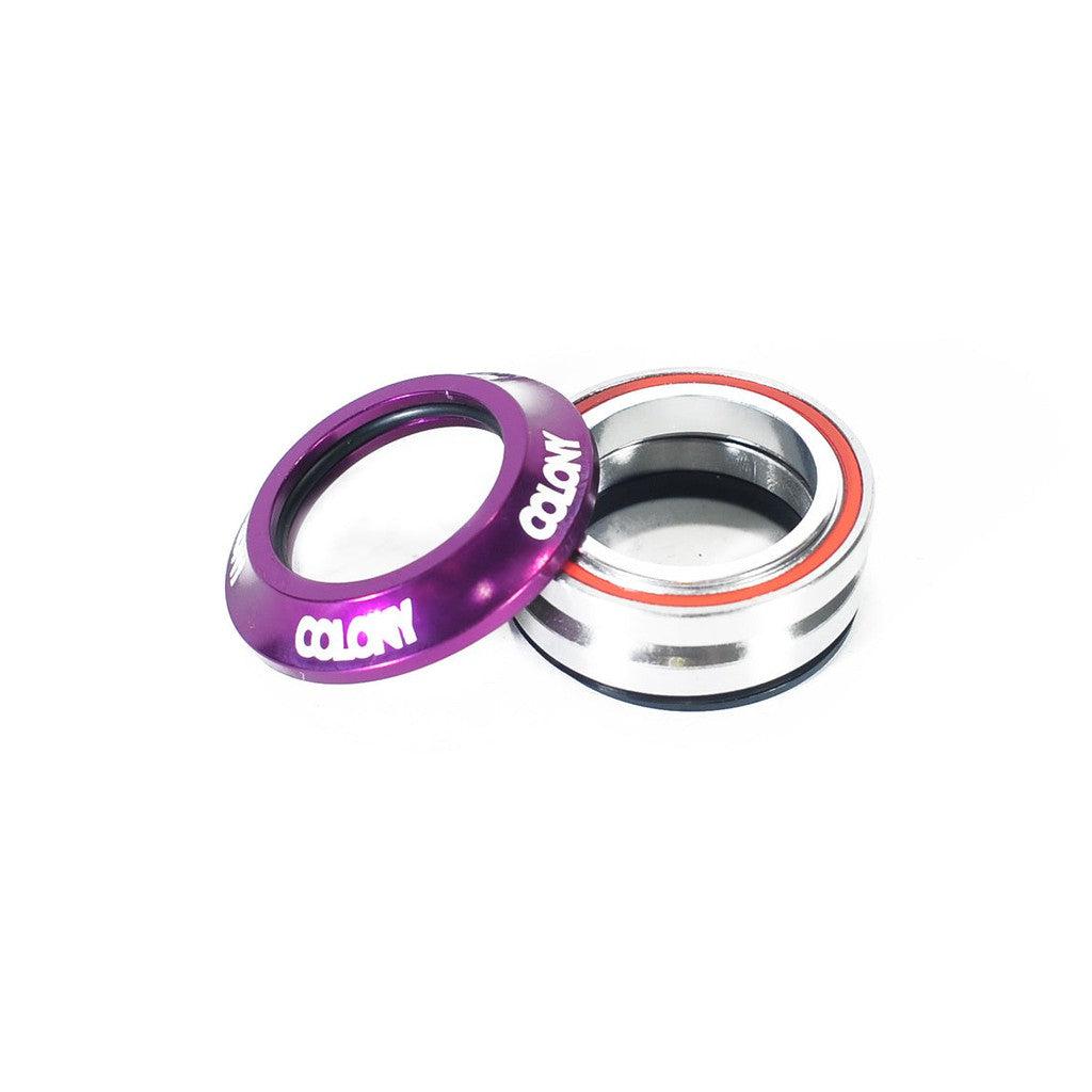 A purple and silver Colony Integrated Headset with the brand name "COLONY" printed in white on the purple part, positioned on a white surface. This high-quality BMX component features durable cartridge bearings for smooth performance.