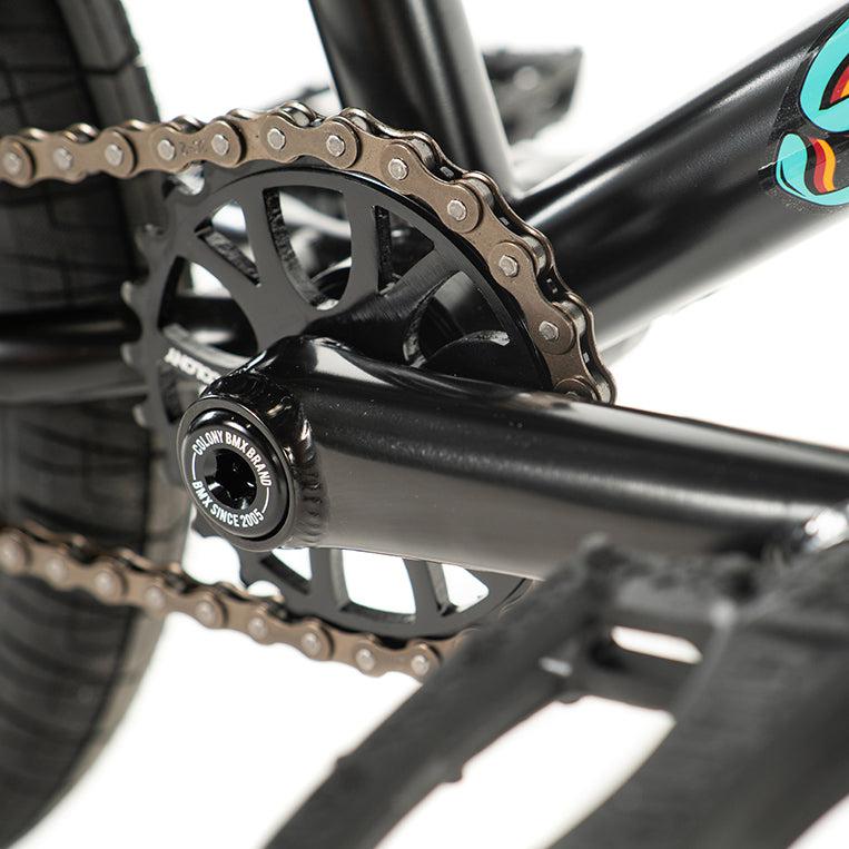 Close-up of a bicycle chain and sprocket on a sleek black frame, reminiscent of the precision found in a Colony Sweet Tooth Pro Elite 16 Inch Bike.