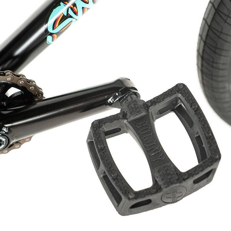 Close-up of a bicycle pedal on a black crank arm, chain, and rear tire in view. This captures the essence of the Colony Sweet Tooth Pro Elite 16 Inch BMX bike.