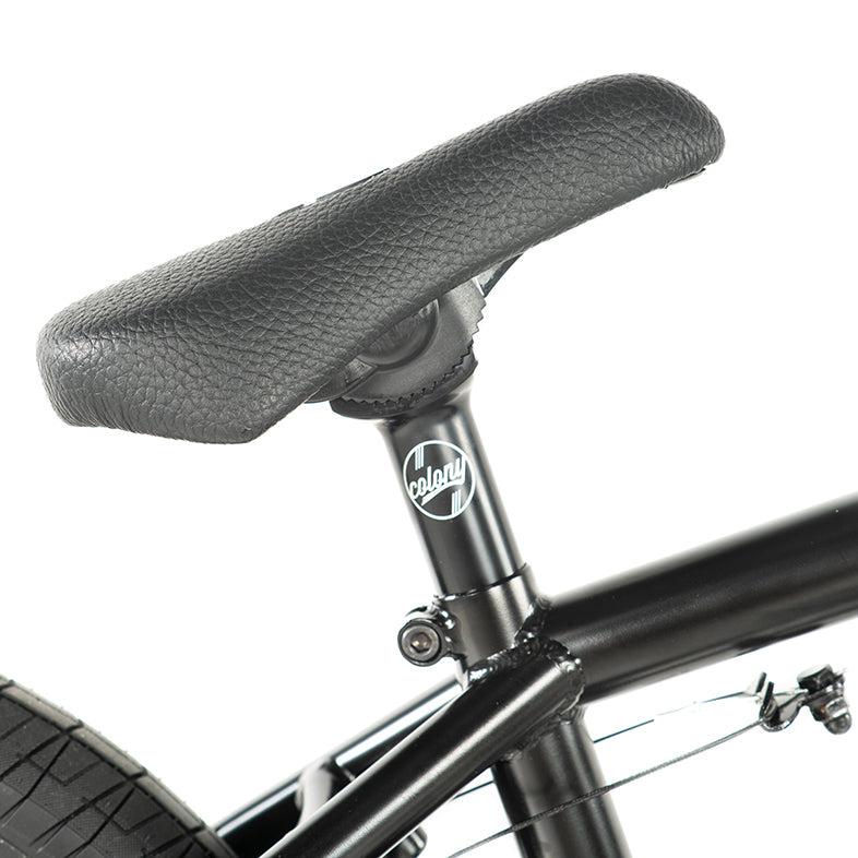 Close-up of the Colony Sweet Tooth Pro Elite 16-inch bike featuring a black seat and seat post with the Colony BMX logo. The frame connects elegantly, hinting at the sleek design visible through its rear tire and brake cable.