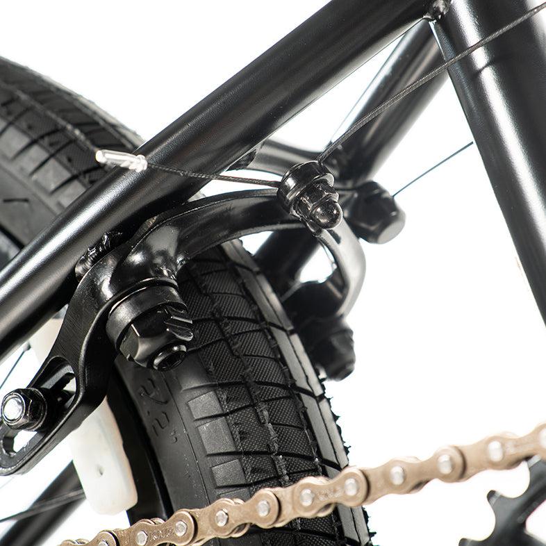 Close-up of a Colony Sweet Tooth Pro Elite 18-Inch BMX bike's rear wheel, highlighting the brake mechanism and chain against a crisp white background.