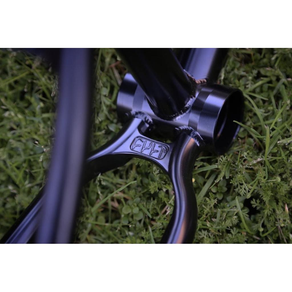 Close-up of the Cult 2 Short IC Frame in black, with visible welding and iconic tubing, resting on green grass.