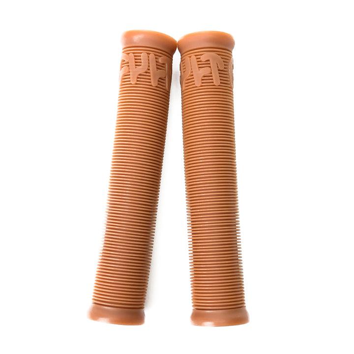 The Cult Crew Grips, a pair of brown, ribbed BMX grips with slightly flared ends made from durable rubber compound, are placed side by side on a white background.