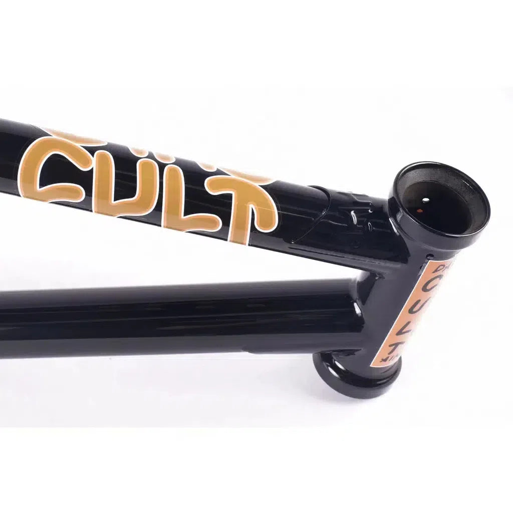 A detailed view of the black Cult Dak Frame showcases the striking orange "CULT" branding. The image highlights the Cult Classic Tubing at the top tube and seat tube junction, capturing Dakota Roche's iconic style.