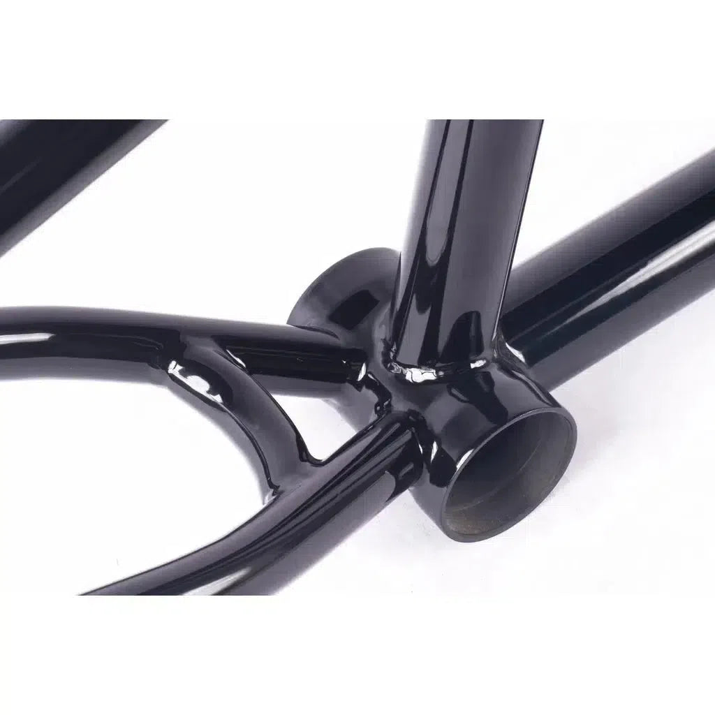 Close-up of a glossy black bicycle frame junction, highlighting the welded connection between the downtube and bottom bracket shell, similar to a Cult Dak Frame.