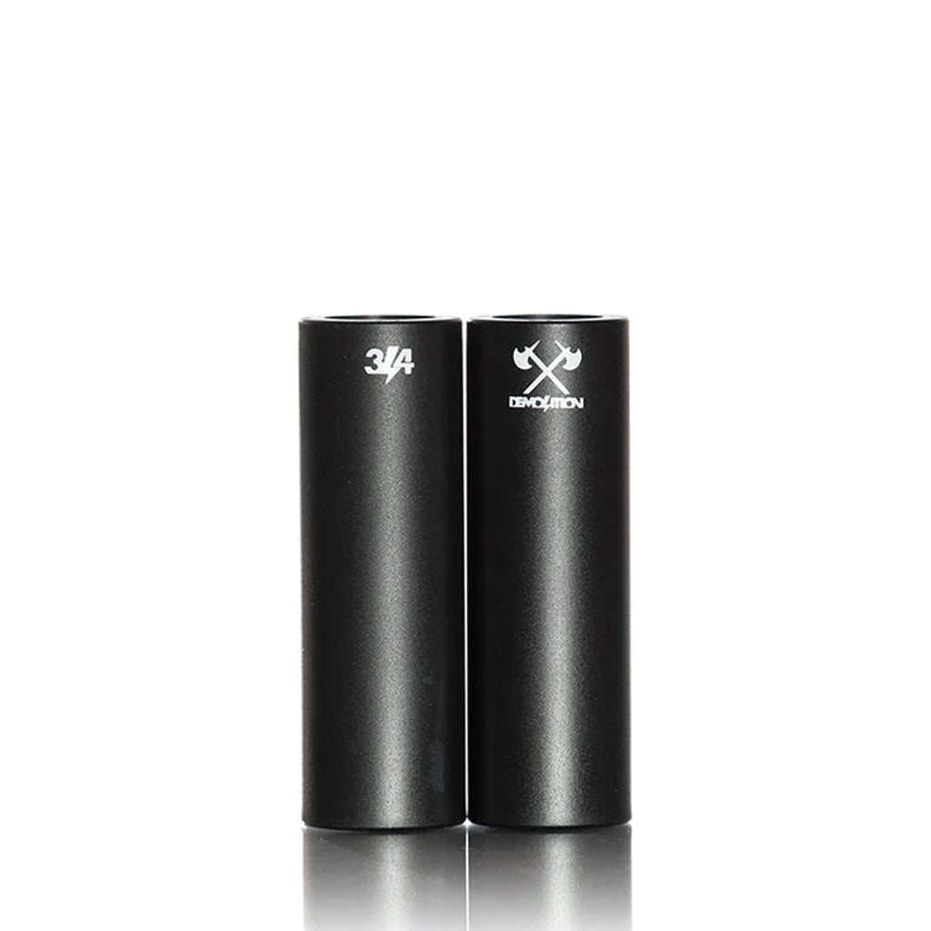 Two black Demolition Axes Pegs (Each) stand upright on a white background; one is labeled "3/4" and the other has a crossed hammer icon with "DEMOLITION," making them durable choices for your next BMX grind session.