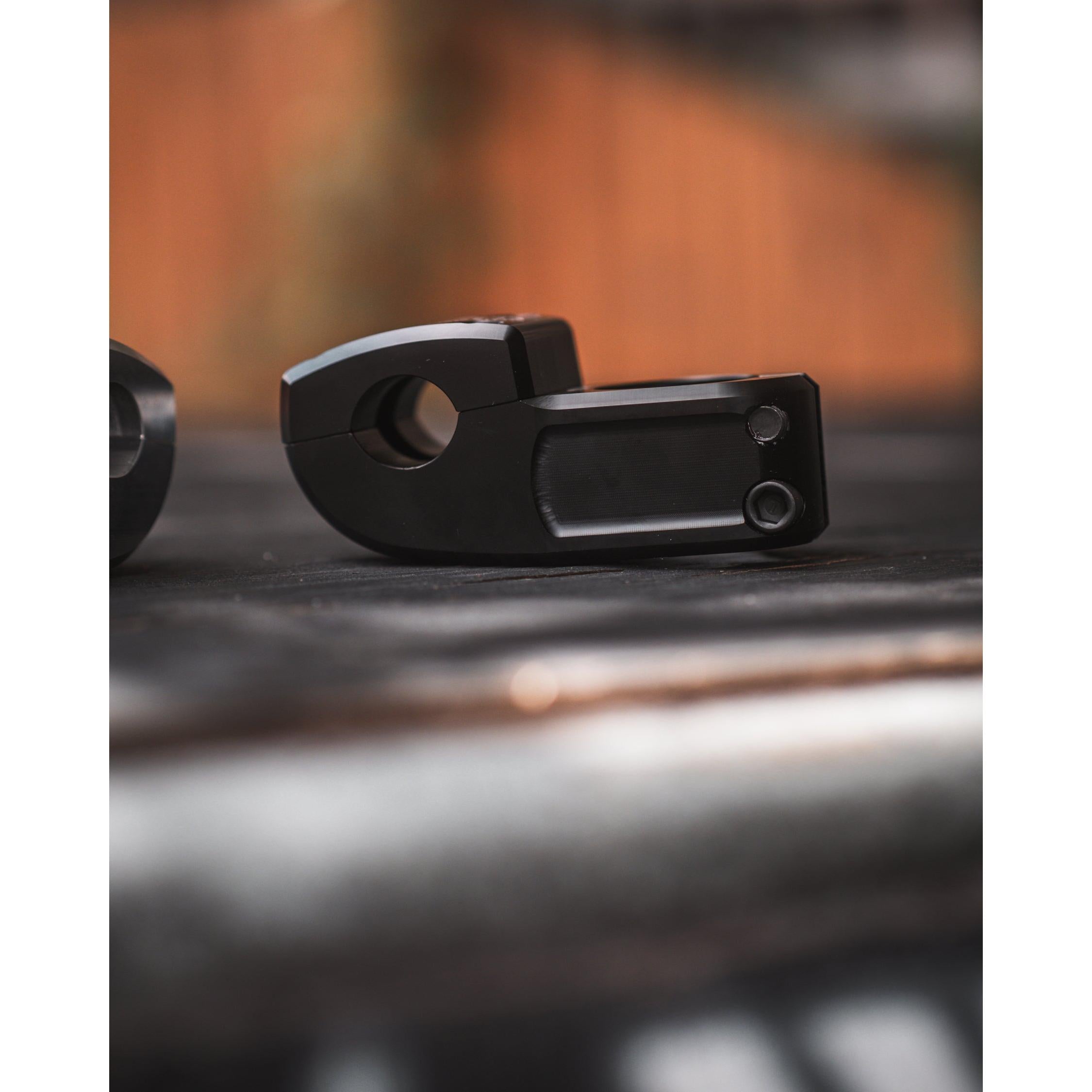 Close-up of a Demolition Josh Dove Stem resting on a surface, with a blurred background highlighting its black metal design.