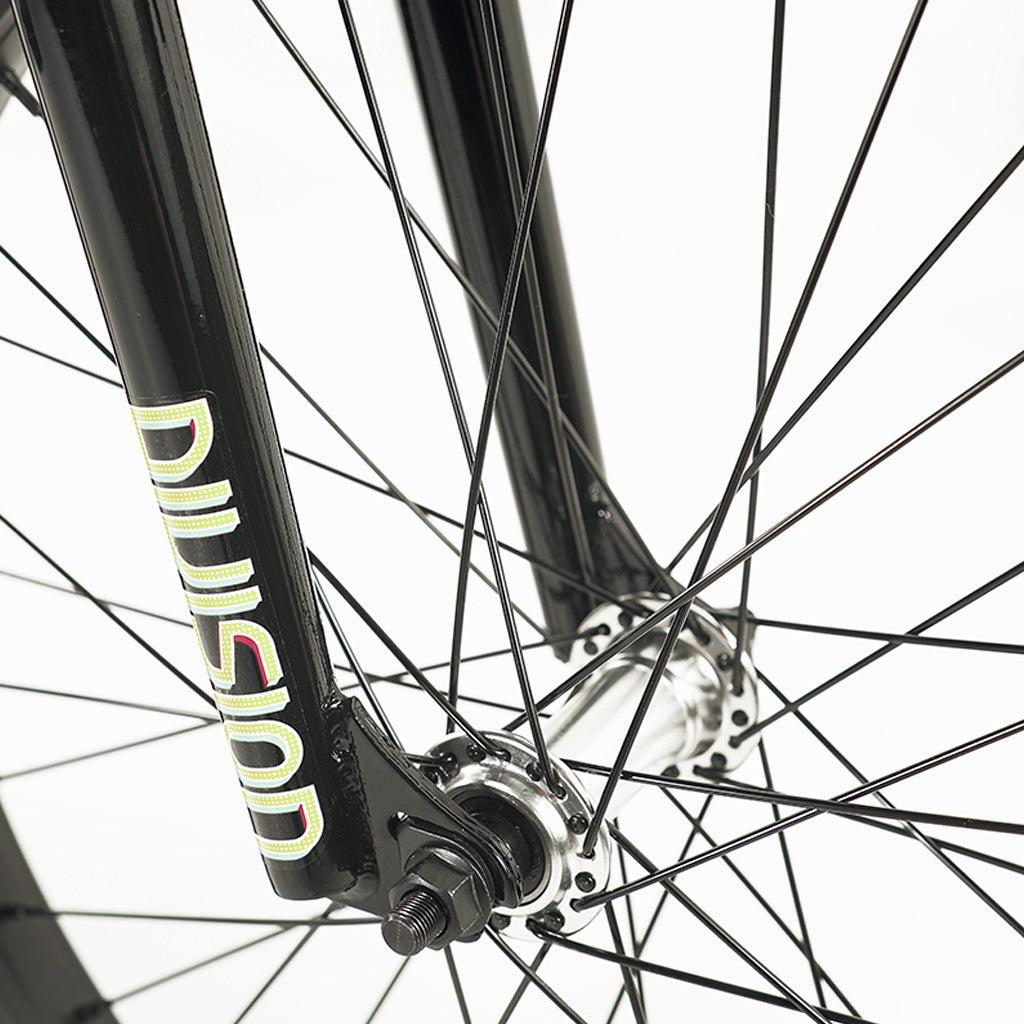 Close-up of a black Division Blitzer 20 Inch Bike front fork and wheel spokes, with the word "Division" visible on the fork. The background is white.