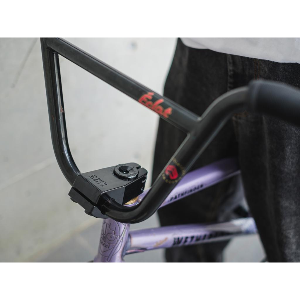 Close-up of BMX bike handlebars featuring black grips on a purple frame with "Eclat" branding, including the limited edition Eclat 1023 Stem for a unique mid-school style that blends form and function.