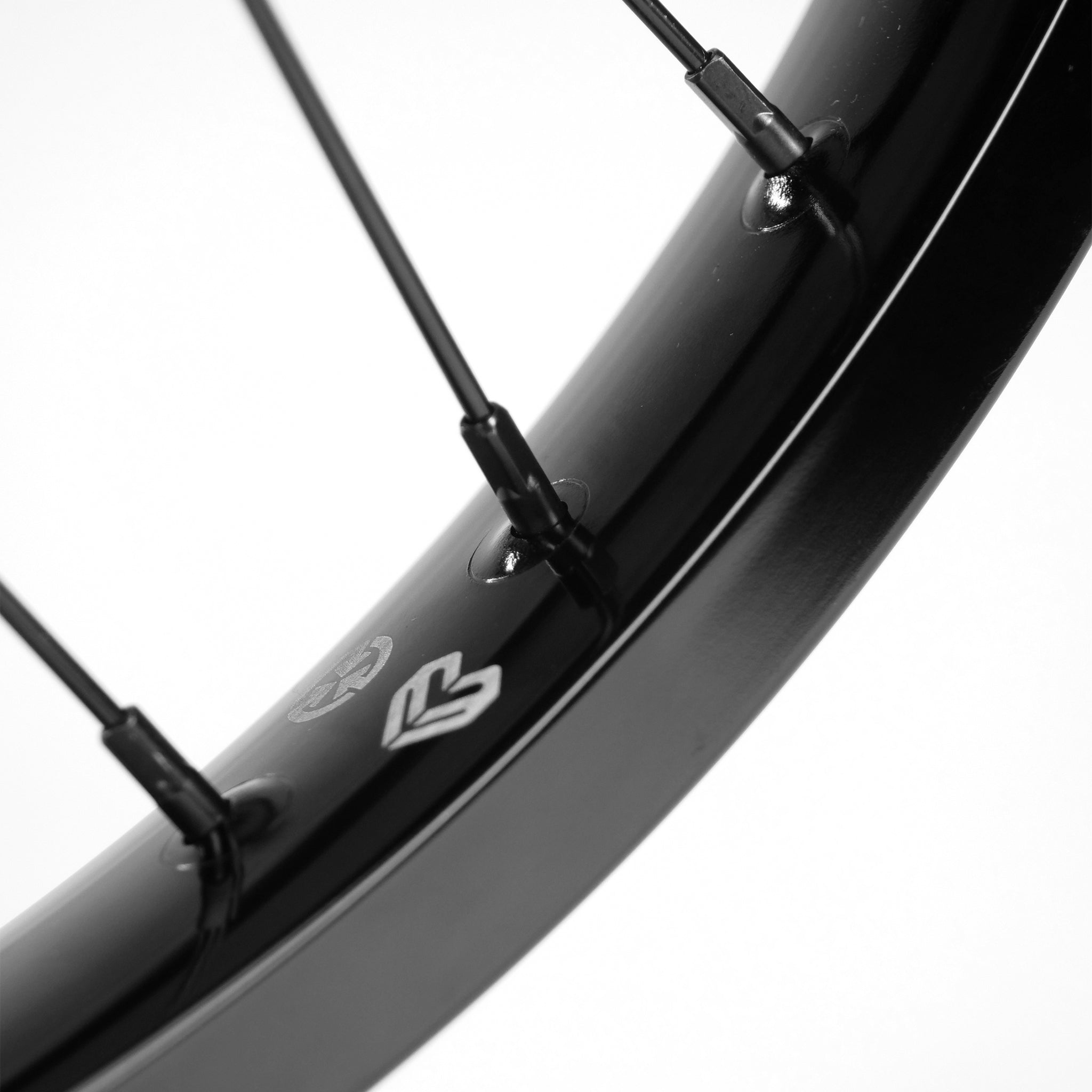 Close-up of a black bicycle wheel featuring Éclat steel spokes, with prominent brand logos on the Eclat Locater / Exile Front Wheel rim.