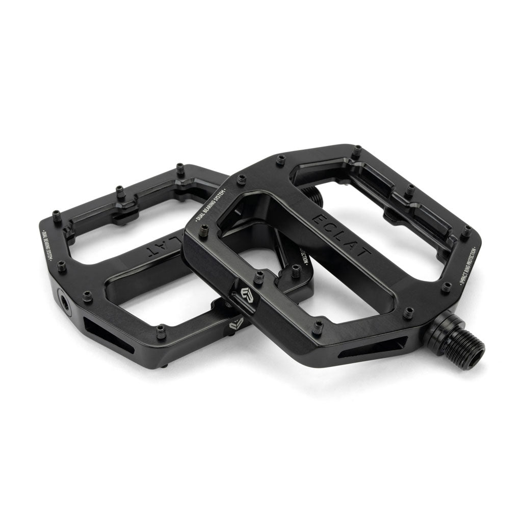 A pair of black Eclat Surge XL Pedals featuring multiple grip pins, an oversize platform area, and a robust dual bearing/bushing spindle system.