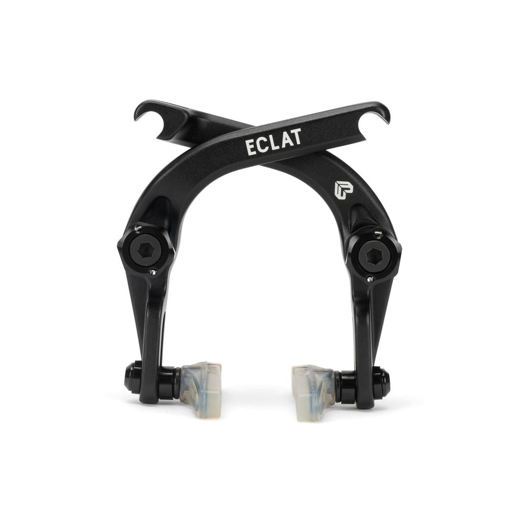 Close-up of a black Eclat Talon Brake with two arms crossed at the top, showcasing labeled components and equipped with Eclat Force brake pads, constructed from cold-forged alloy.