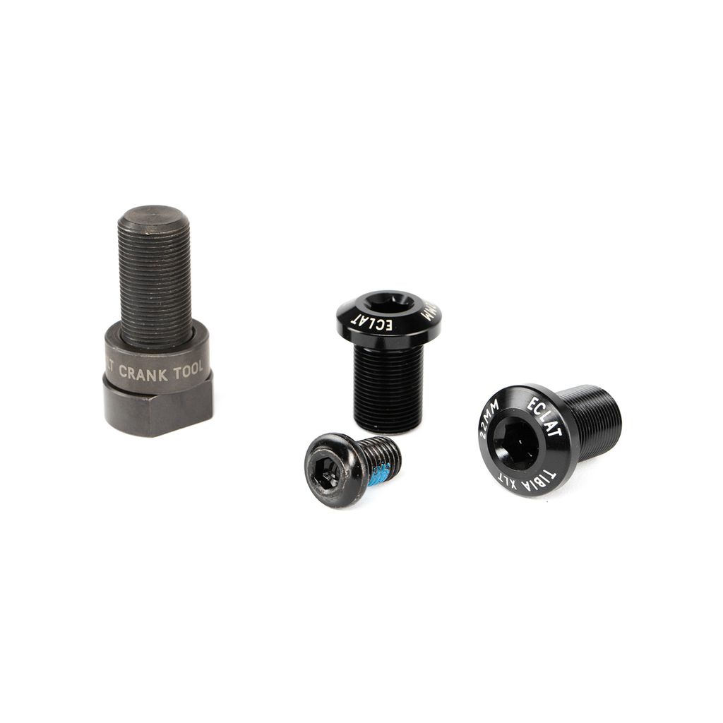 Four black bike crank and stem bolts of various sizes are arranged on a white surface. One bolt is labeled "CRANK TOOL," another is labeled "ECLAT," and they belong to the superlight version of the Eclat Tibia XLT Cranks, known for its lightweight crank design.