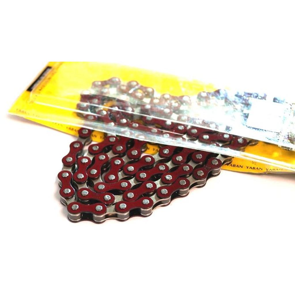 A YBN S-410 Full Link Chain in red is partially removed from its yellow plastic packaging.