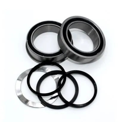 Two metal ball bearings and four circular washers—two black, two silver—are displayed on a white surface, showcasing parts designed for durability similar to the Black Bearing B5 BB86 30mm Thru Bottom Bracket.