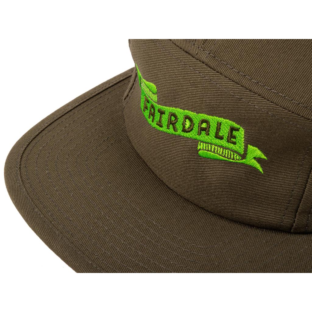 Close-up of a brown Fairdale Banner Camper Cap featuring green embroidered "FAIRDALE" text on the front panel.