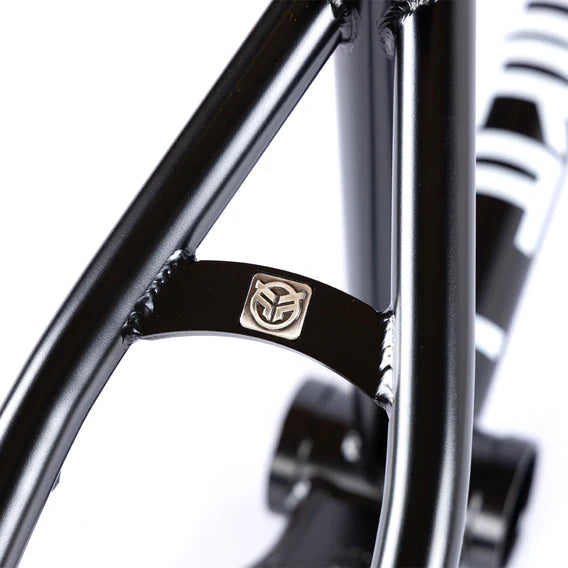Close-up of the Federal Bruno ICS2 Frame, a black BMX frame crafted from 4130 Chromoly tubing, showcasing a small metallic emblem with a stylized face on the rear triangle near a welded joint.