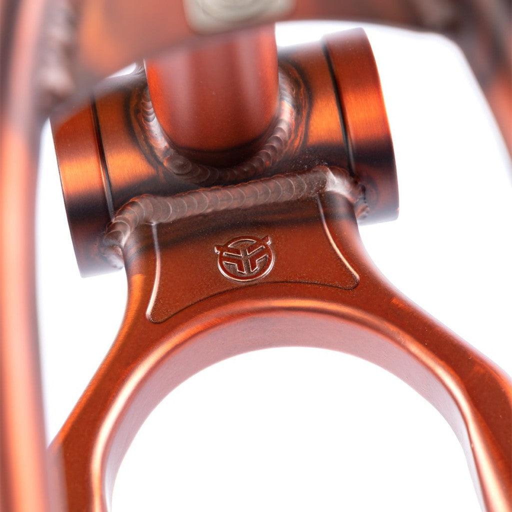 Close-up of an orange Federal Boyd 18 Inch ICS2 Frame for children's BMX bikes, showing visible welds, a circular cutout, and an engraved logo on the metal surface.