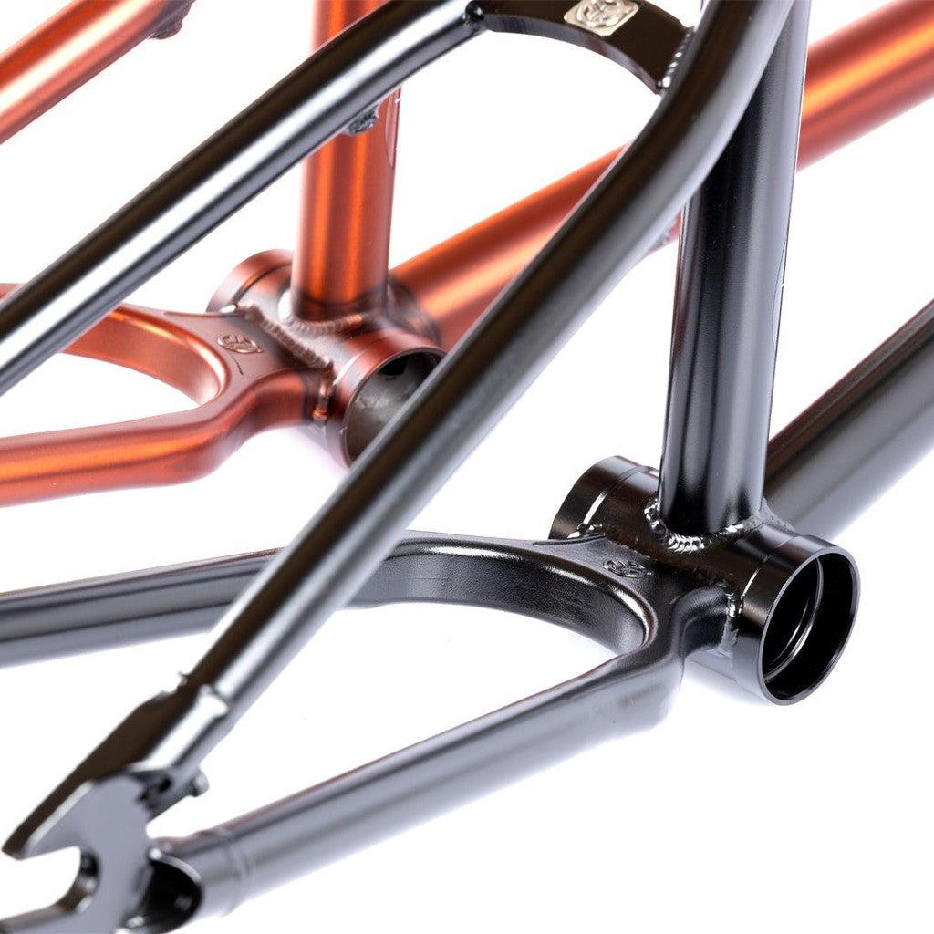 Close-up of two bicycle frames, featuring a Federal Boyd 18 Inch ICS2 Frame in glossy black and an orange kids bike frame, with a focus on the bottom bracket and rear stays.