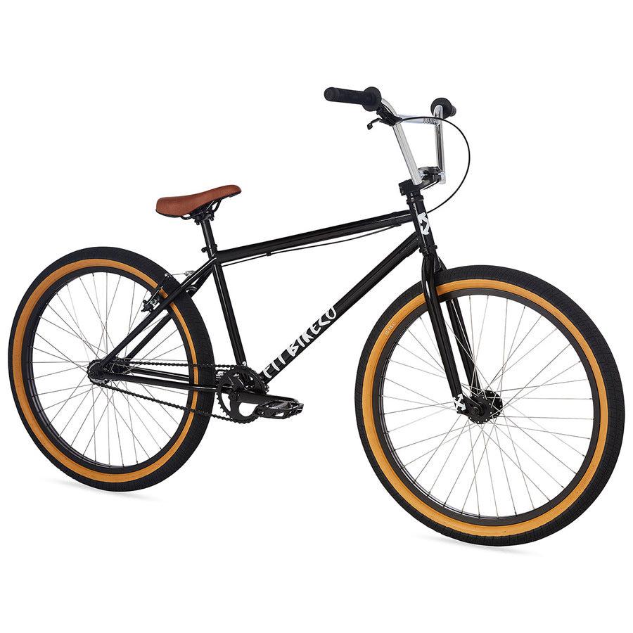 The Fit CR26 Inch Bike, shown on a white background, features a black cr-mo frame, brown seat, and orange-rimmed tires.