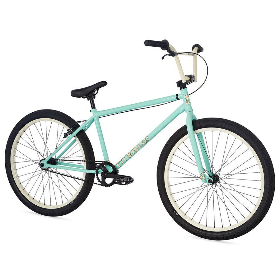 The Fit CR26 Inch Bike is a mint green BMX with a cr-mo frame, black seat, handlebars, pedals, whitewall tires, and a simple frame design.