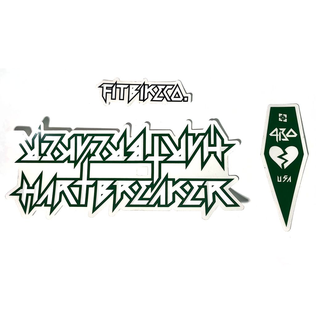 The Fitbikeco Hartbreaker Frame Decal Set features three unique decals: one with the text "FITBIKECO.," another with stylized text "HEARTBREAKER," and a green shield sticker displaying a broken heart alongside "420 USA." Perfect for freshening up your Hartbreaker frame, these replacement stickers bring a distinct touch to any bike.