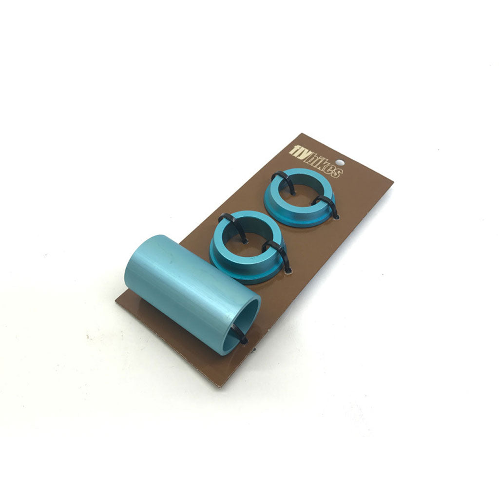 A set of three turquoise Fly 22mm Spanish BB Spacers on brown cardboard, featuring black clips attached to the spacers.
