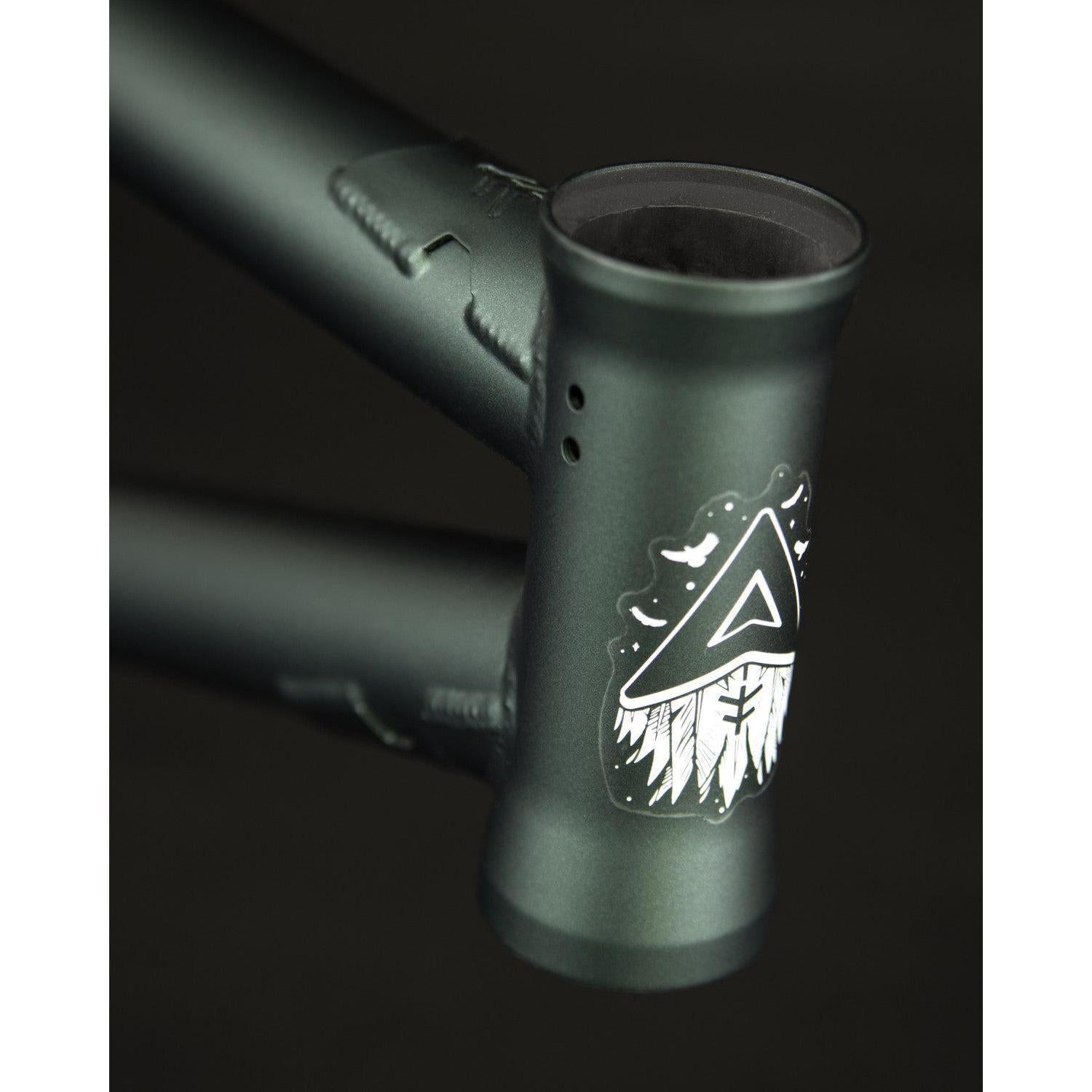 Close-up of the 4130 Cr-Mo Fly Bikes Aire Frame head tube in matte green, displaying a white triangle and stylized feathers graphic on the front.